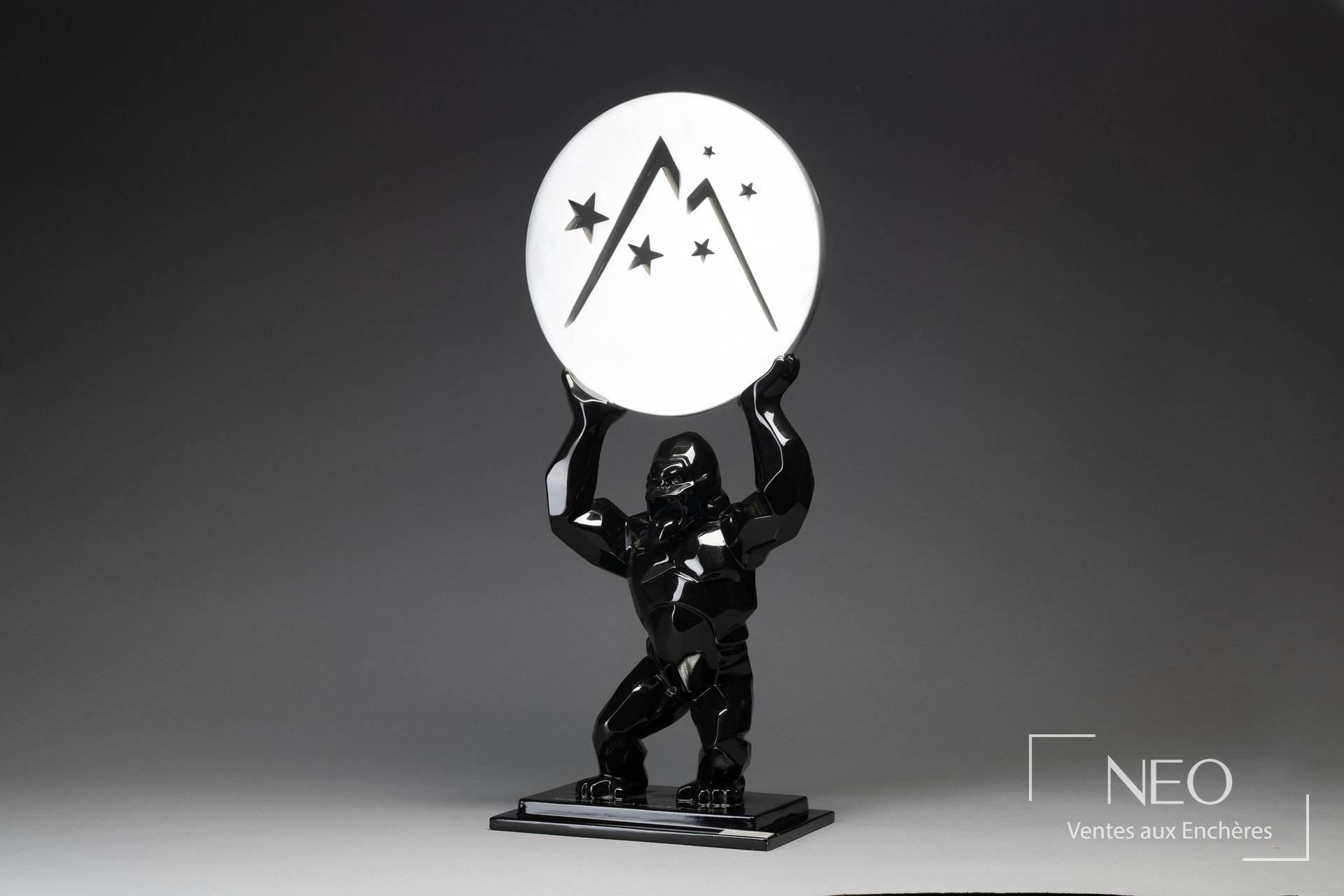 Sculpture Kong noire tenant un disque argenté décoré d'étoiles
