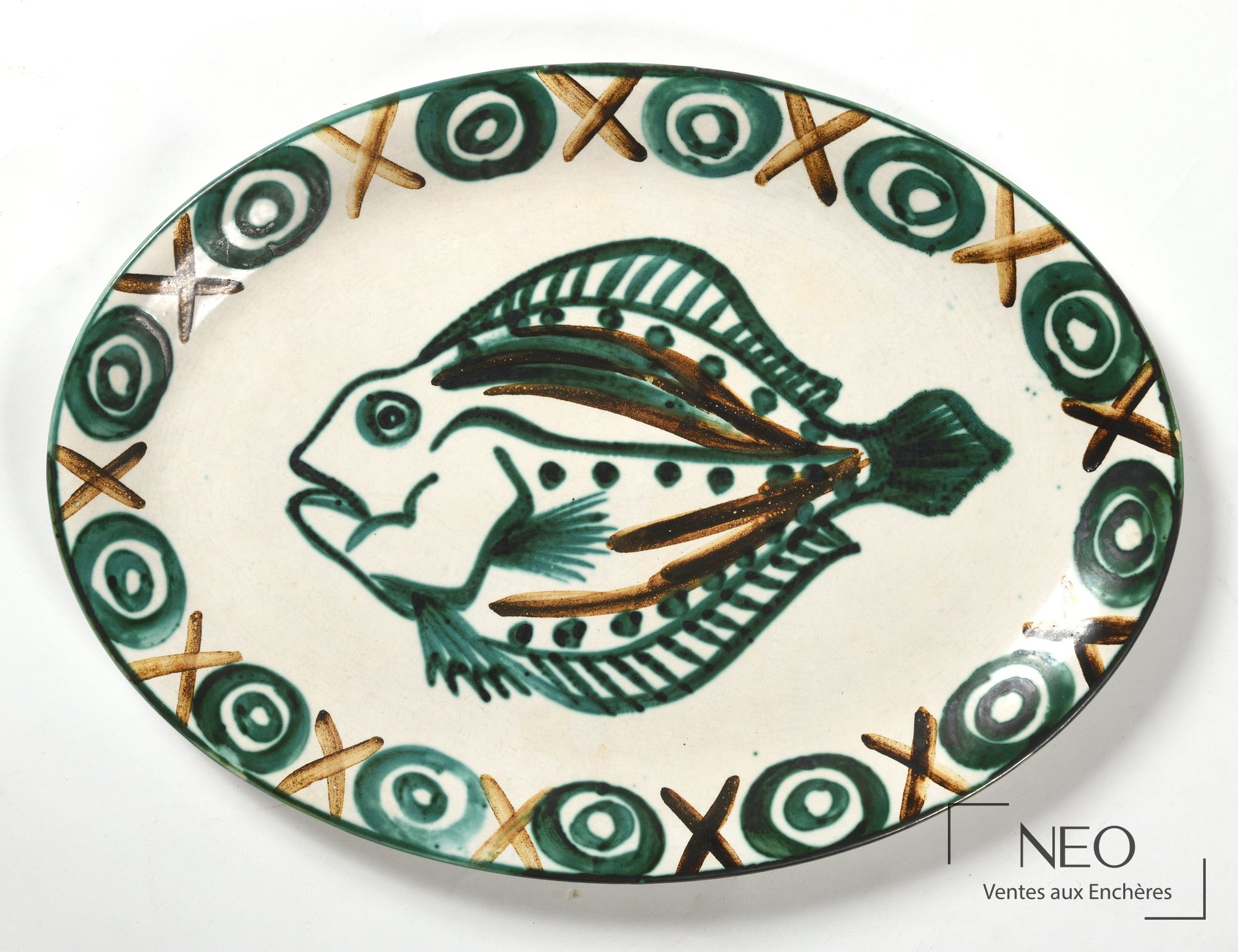 Plat ovale en céramique décoré d'un poisson et de motifs géométriques verts et bruns