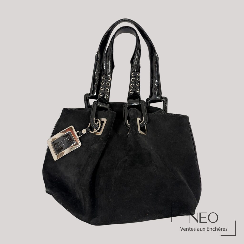 Sac noir en daim avec anses brillantes et bijou de sac rectangulaire.