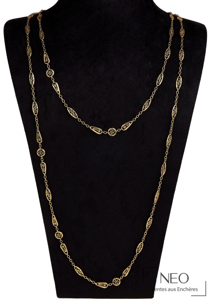 Sautoir en or jaune à maille filigrane présenté sur support noir