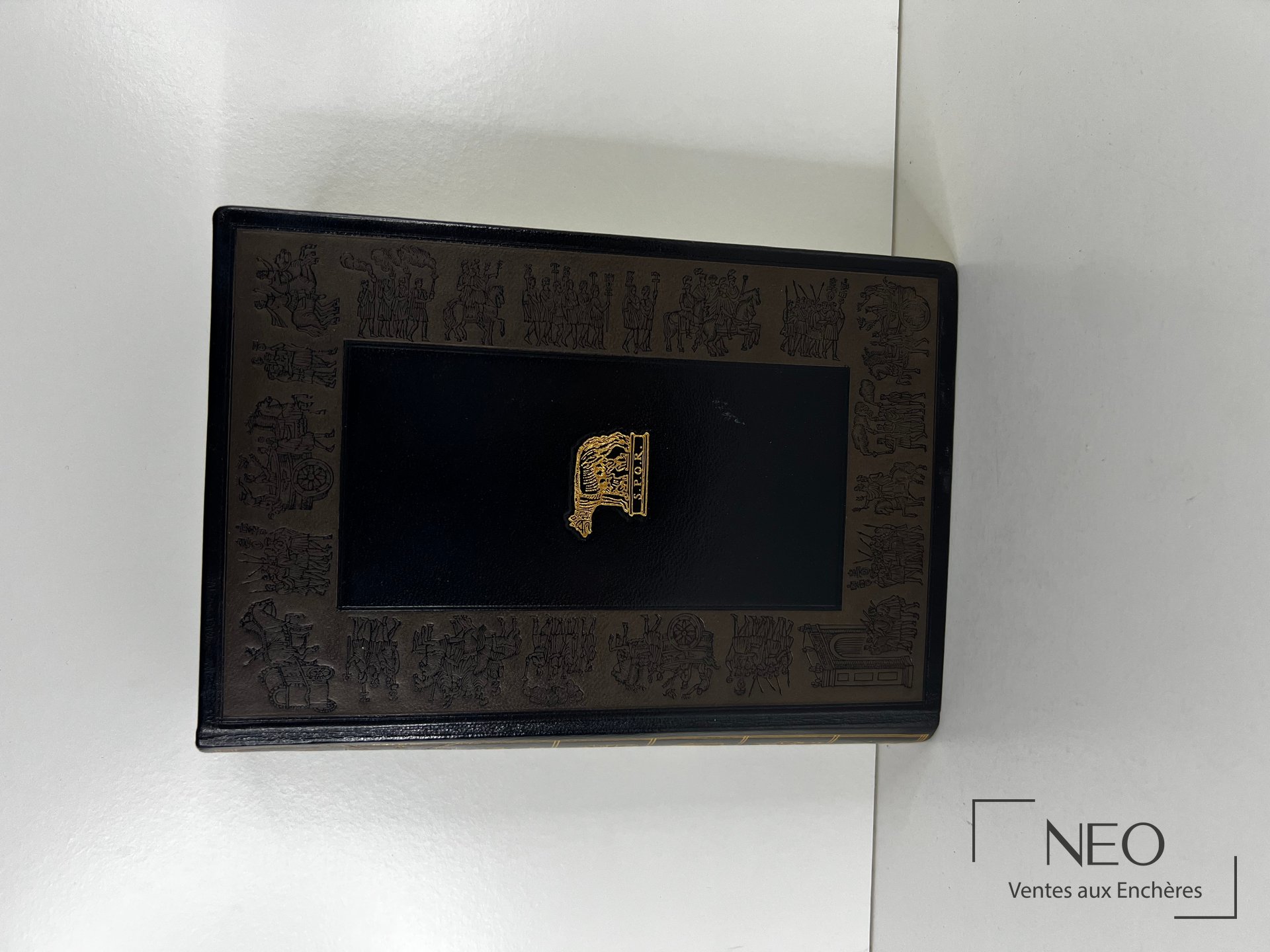 Couverture noire ornée de dorures avec titre central et décor de vignettes.