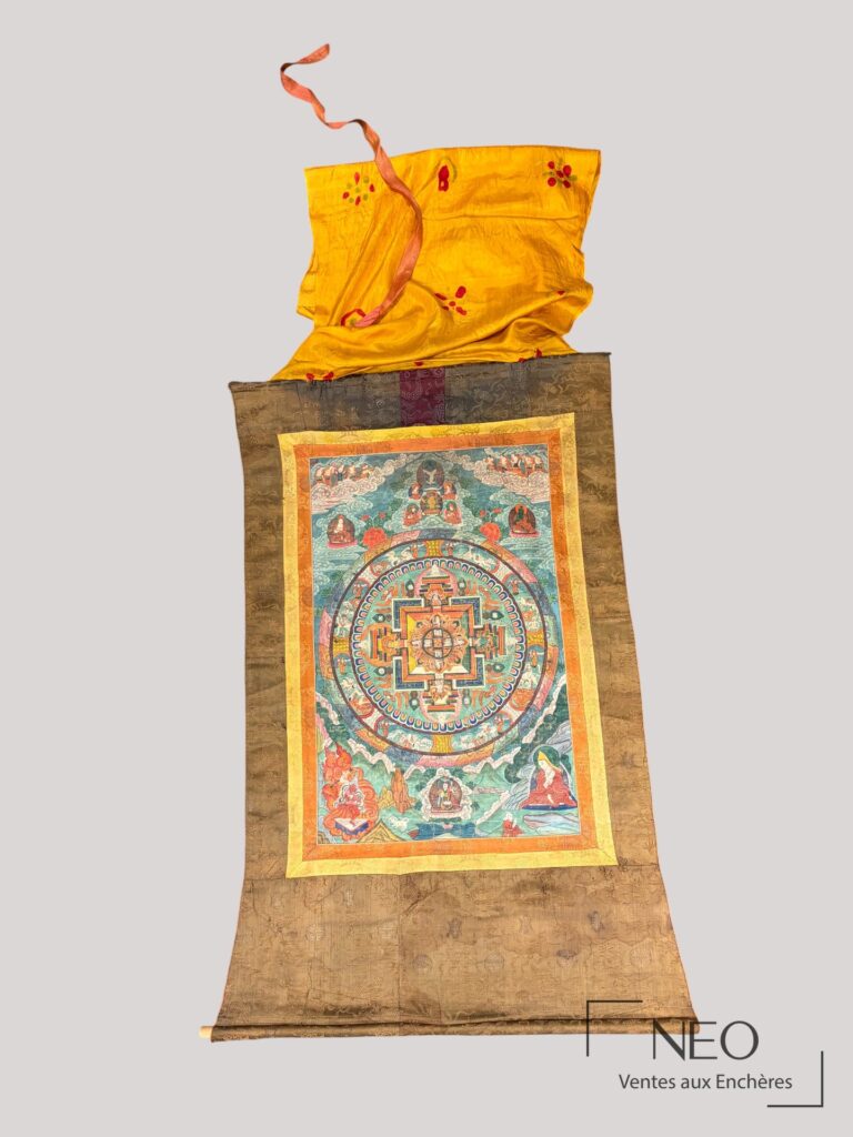 Mandala tibétain présenté en longueur dans son entourage de soie brodée.