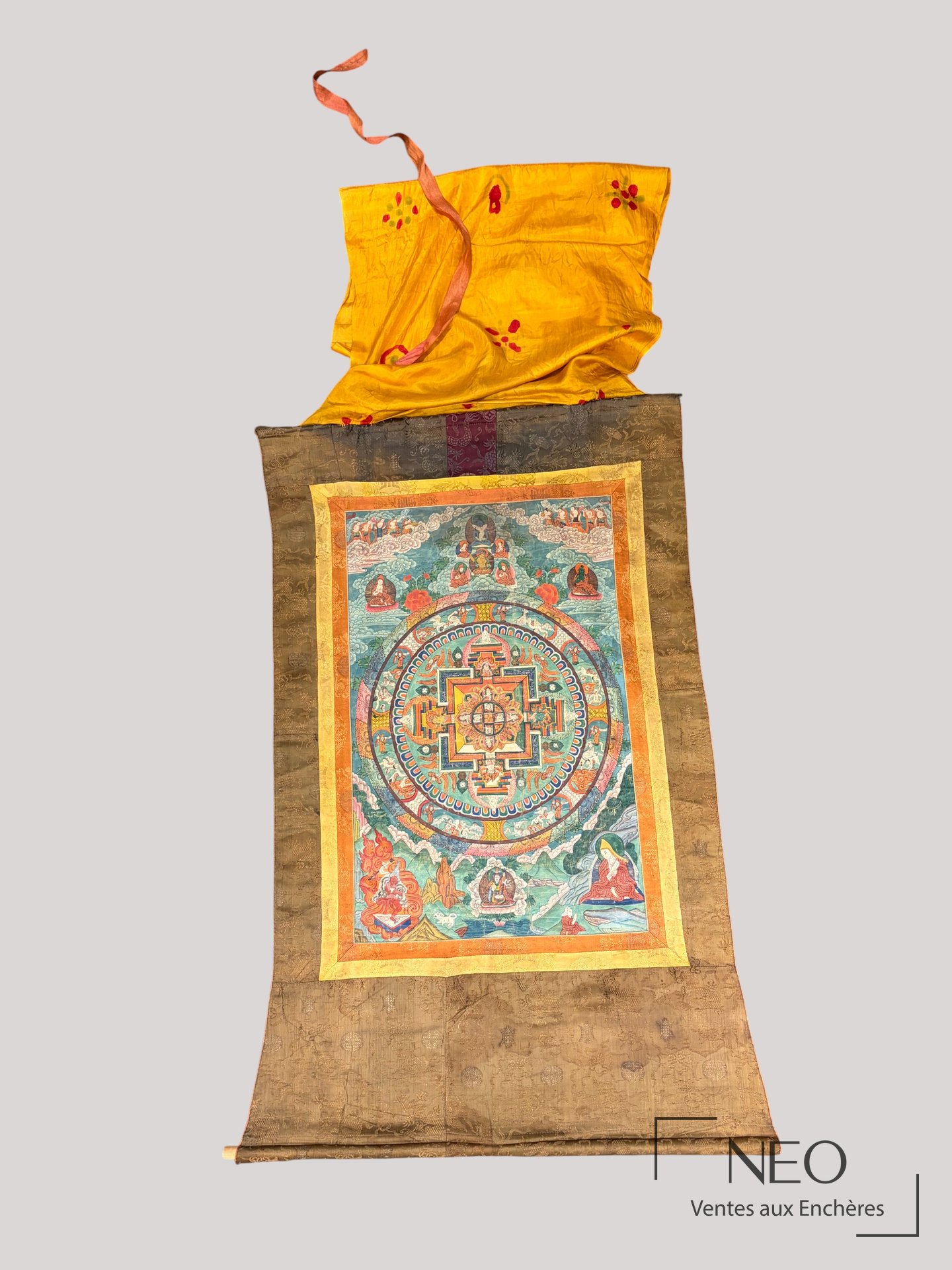 Mandala tibétain présenté en longueur dans son entourage de soie brodée.