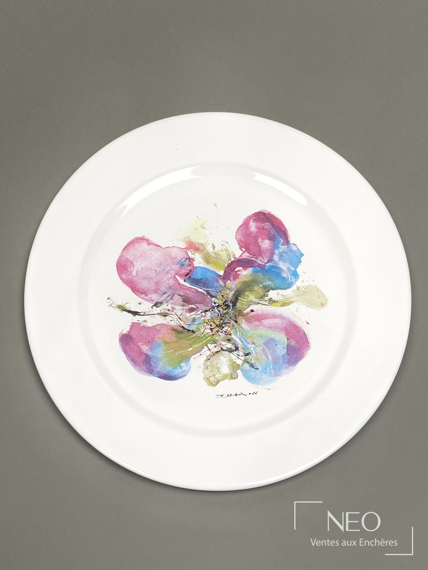 Assiette large en faïence blanche à décor floral polychrome au centre