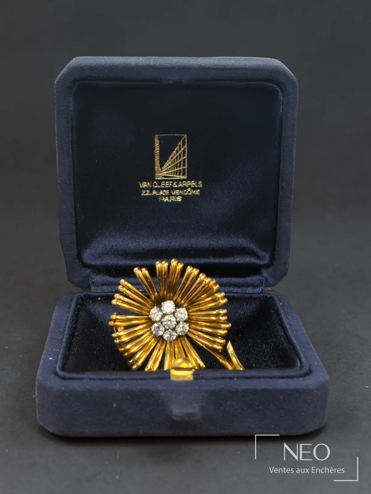 Broche fleur Van Cleef & Arpels présentée dans son écrin bleu marine de la place Vendôme